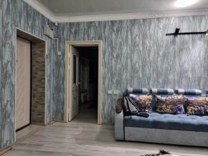 Habitación con sofá y pared con papel pintado azul. en Deluxe, en Shymkent