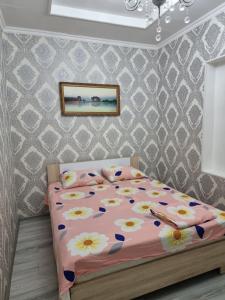 Un dormitorio con una cama con flores. en Deluxe, en Shymkent