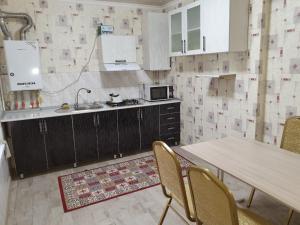 a kitchen with a table and chairs and a sink at Deluxe in Shymkent