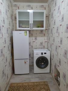 a kitchen with a refrigerator and a washing machine at Deluxe in Shymkent