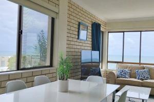 a living room with a table and chairs and windows at Ocean view beachside 3 bedroom 2 bathroom unit in Caloundra