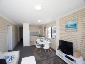 a living room with a table and a tv and a kitchen at Ocean view beachside 3 bedroom 2 bathroom unit in Caloundra