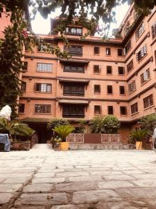 a large brick building with plants in front of it at Courtyard Pujan Hotel in Kathmandu