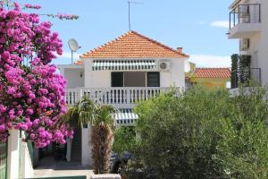 a white house with pink flowers in front of it at Apartments Big - free parking in Vodice