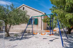 un parque infantil con un columpio naranja y azul en Holiday home Diana - with pool, en Pučišća