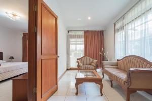 a bedroom with a bed and a couch and a table at Dequr Hotel Dipati Ukur Mitra RedDoorz in Bandung +29 photos