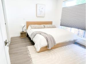 a bedroom with a bed with white sheets and a window at *NEW* HAVN HOUSE MODERN RETREAT - STEPS FROM BEACH in Penticton