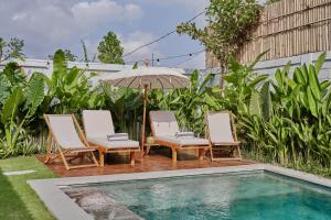 a group of chairs and an umbrella next to a pool at New Villa La Crema - Designer 3BR Canggu in Canggu