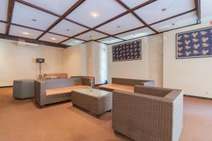 sala de estar con muebles de mimbre, mesa y sillas en Dequr Hotel Dipati Ukur Mitra RedDoorz, en Bandung