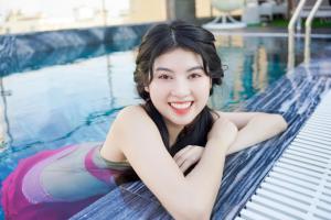 une jeune femme qui se couche dans une piscine dans l'établissement Sea Wind Hotel by THG, à Đà Nẵng