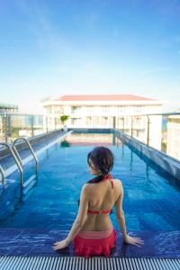 una mujer en bikini sentada en una piscina en Sea Wind Hotel by THG, en Da Nang