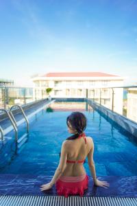 a woman in a bikini sitting in a swimming pool at Sea Wind Hotel by THG in Danang