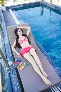 a woman in a bikini laying on a mattress next to a swimming pool at Sea Wind Hotel by THG in Da Nang