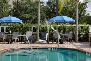 a swimming pool with chairs and umbrellas and a fountain at Fairfield Inn and Suites by Marriott Titusville Kennedy Space Center in Titusville