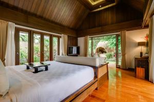 a bedroom with a large bed and a large window at The Samaya Ubud in Ubud