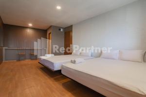 two beds in a room with white walls and wooden floors at D'Valley View Lembang Mitra RedDoorz in Lembang