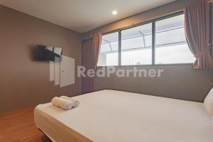 a bedroom with a white bed and a window at D'Valley View Lembang Mitra RedDoorz in Lembang