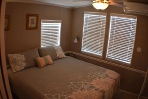 um quarto com uma cama, uma ventoinha de tecto e janelas em Pelican's Roost, Waterfront comfort at Venture Out em Cudjoe Key
