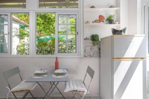 een tafel en stoelen in een keuken met ramen bij Apt La Source - Plage à 5min - Nature & Calme in Les Trois-Îlets