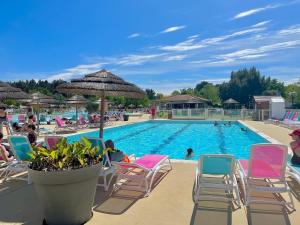 a swimming pool with chairs and an umbrella at Bungalows climatisés en 3 ou 4ch - jusqu'à 18 voyageurs - mh732 3ch ou mh828 4ch Biscarrosse Lake-proche océan in Gastes