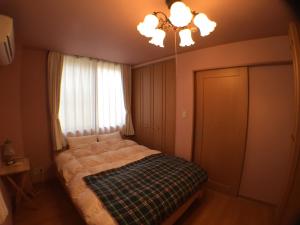 1 dormitorio con cama, lámpara de araña y ventana en Cheese Cozy Condo, en Tokio