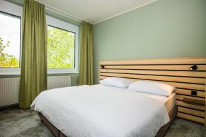 a bedroom with a white bed and two windows at flexymotel Spielberg in Spielberg