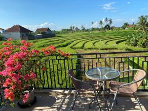 a patio with a table and chairs and a field of flowers at Canggu - Pererenan Guesthouse " aBaliHouse " in Canggu