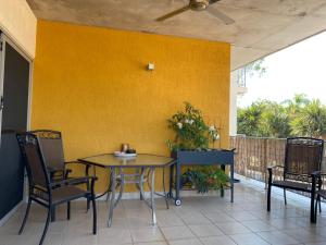 a patio with a table and chairs and a yellow wall at Mauna Loa Apartment in Darwin