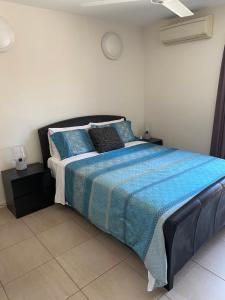 a bedroom with a bed with a blue blanket and pillows at Mauna Loa Apartment in Darwin