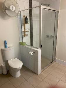 La salle de bains est pourvue de toilettes et d'une douche en verre. dans l'établissement Mauna Loa Apartment, à Darwin