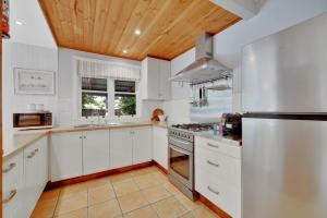 a kitchen with white cabinets and a wooden ceiling at Home Away From Home Little White Cottage Mudgee in Mudgee