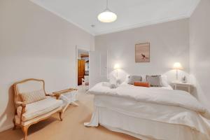 a white bedroom with a large bed and a chair at Home Away From Home Little White Cottage Mudgee in Mudgee