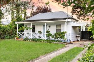 a white house with a porch and a yard at Home Away From Home Little White Cottage Mudgee in Mudgee