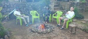 Eine Gruppe von Menschen, die um ein Feuer herum sitzen in der Unterkunft Mai Kilimanjaro Home Stay in Marangu