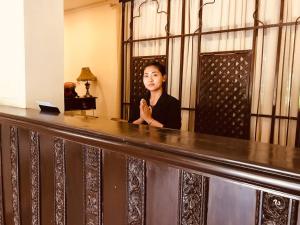 een vrouw achter een bar in een kamer bij Courtyard Pujan Hotel in Kathmandu