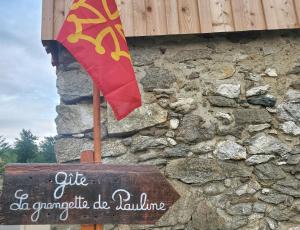 a flag on the side of a stone building with a sign at Gite La Grangette de Pauline in Mercus-Garrabet
