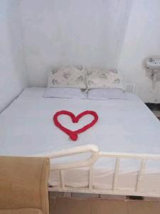 Una cama blanca con un corazón rojo. en SOFA CAMP NAIVASHA, en Naivasha