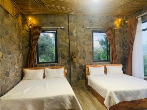 duas camas num quarto com duas janelas em Homstay Gốc Vải em Dan Mey