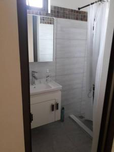 ein weißes Badezimmer mit einem Waschbecken und einem Spiegel in der Unterkunft Arc en Ciel 1 - 3 bedrooms Private Appartment in Flic-en-Flac