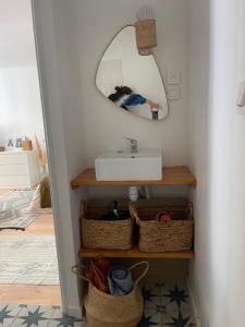 een badkamer met een wastafel, een spiegel en manden bij La Casa Lola in Rians