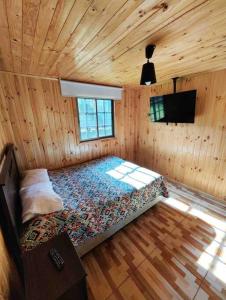 een slaapkamer met een bed in een houten hut bij Excelente cabaña en Algarrobo in Algarrobo