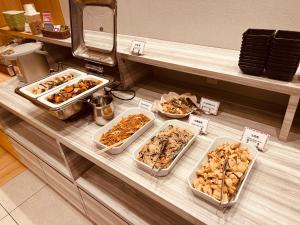 un buffet avec plusieurs plateaux de nourriture sur un comptoir dans l'établissement Smile Hotel Kanazawa Nishiguchi Ekimae, à Kanazawa