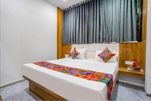 um quarto com uma grande cama branca com lençóis coloridos em FabHotel Western Inn em Surat