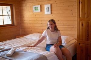 a girl sitting on a bed in a bedroom at Bungalow in Miedzyzdroje with a terrace in Międzyzdroje