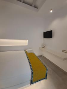 a white room with a couch and a tv on a wall at Margaret's Houses in TINOS Town in Tinos Town