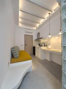 a white kitchen with a bench with a yellow blanket at Margaret's Houses in TINOS Town in Tinos Town