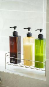 drei Flaschen Seife auf einem Regal im Badezimmer in der Unterkunft ヴィラ バルゴ in Inbu