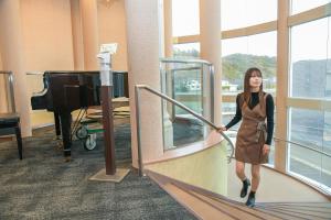 a woman walking down a staircase in a room with a piano at Amakusa Santacoming Hotel in Amakusa