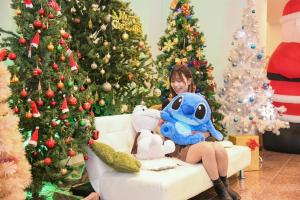 a young girl sitting on a couch in front of christmas trees at Amakusa Santacoming Hotel in Amakusa