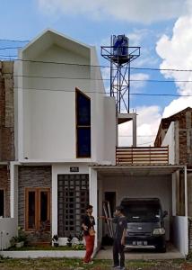 Duas pessoas à porta de uma casa com um camião. em Ambarukmo Green Hill / MA 8 em Yogyakarta